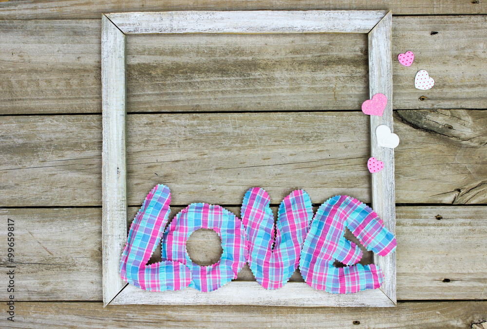 The word LOVE in pink and blue fabric on rustic wood frame with hearts