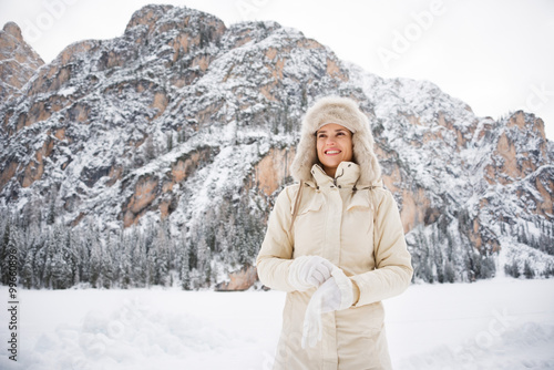 Woman in coat and fur hat wearing gloves while standing outdoors