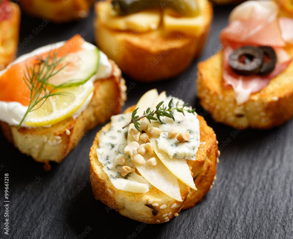 Small canape with grilled baguette with the addition of blue cheese,apple slices, cashew nuts and fresh thyme on black background Small canape with grilled baguette with the addition of blue cheese,apple slices, cashew nuts and fresh thyme on black background