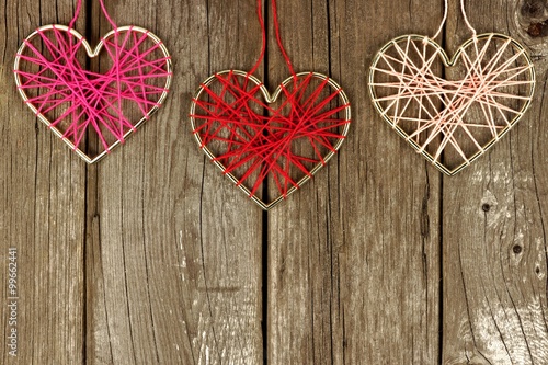 Valentines Day yarn hearts forming a top border on a rustic wood background