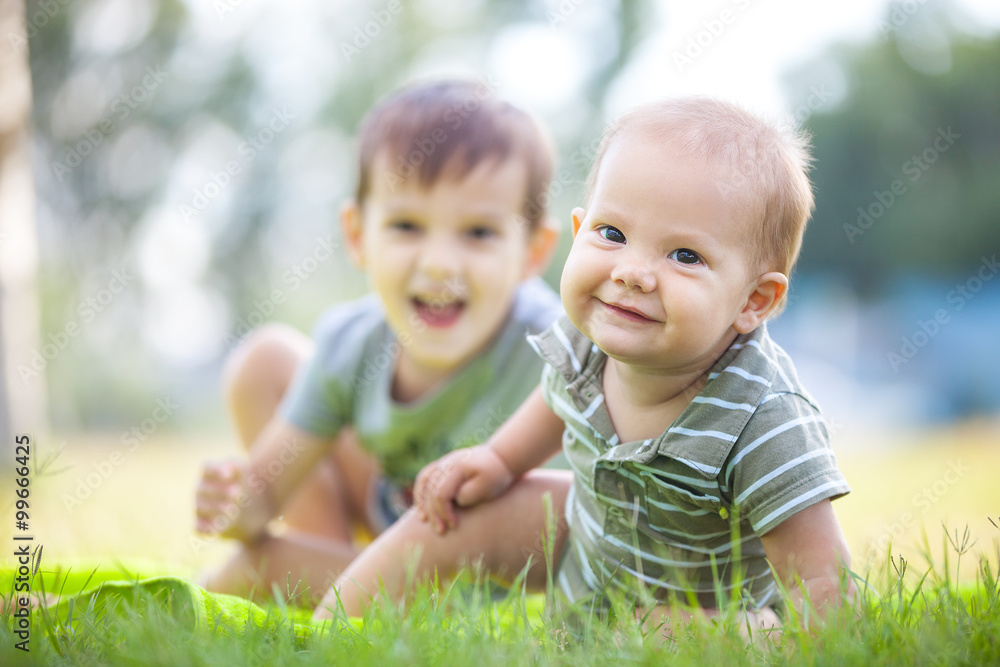 Two happy brothers playing on grass in park Two happy brothers playing on grass in park