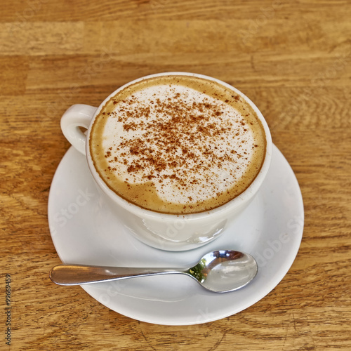 Cappuccino in white cup close-up on wood background
