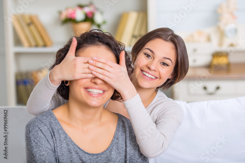 Young girl covering her sisters eyes. 