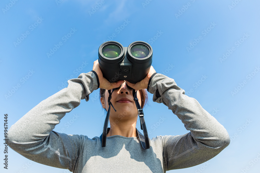 Woman use of the binoculars with clear blue sky Woman use of the binoculars with clear blue sky