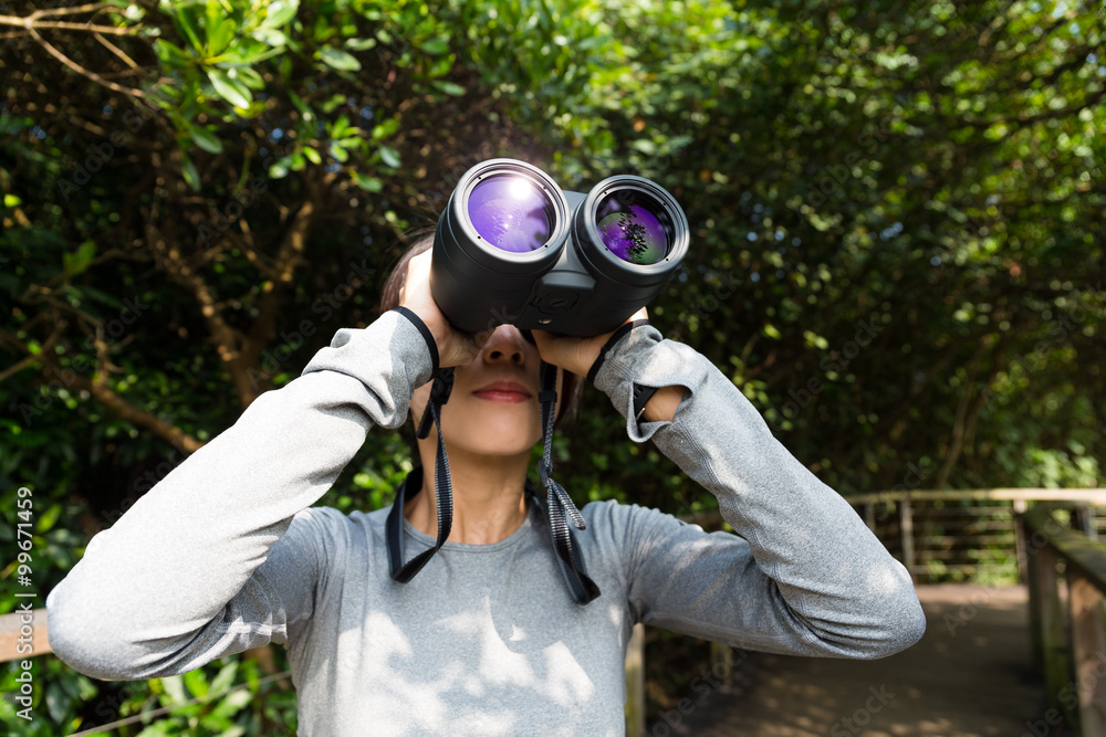 Woman looking though binoculars at jungle Woman looking though binoculars at jungle