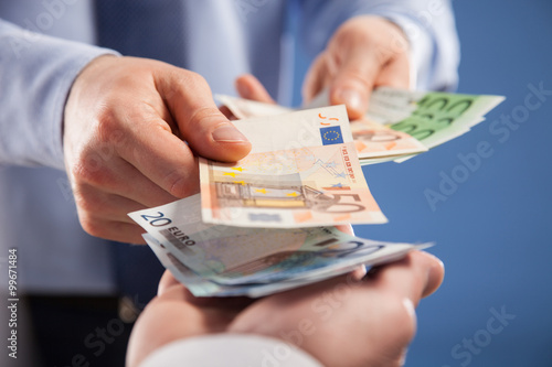 Businessman's  hands exchanging euro on blue background