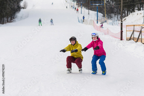Young couple snowboarders slide down the slope in a winter day. Happy couple athletes.