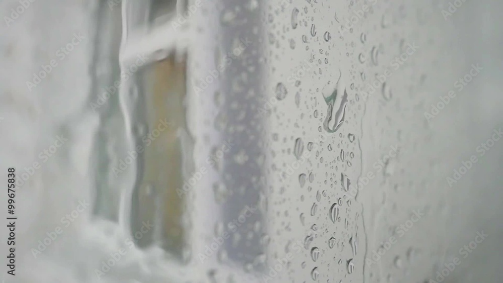 Urban view of rain drops falls on a window during a stormy day overlooking city skyline in the background Urban view of rain drops falls on a window during a stormy day overlooking city skyline in the background
