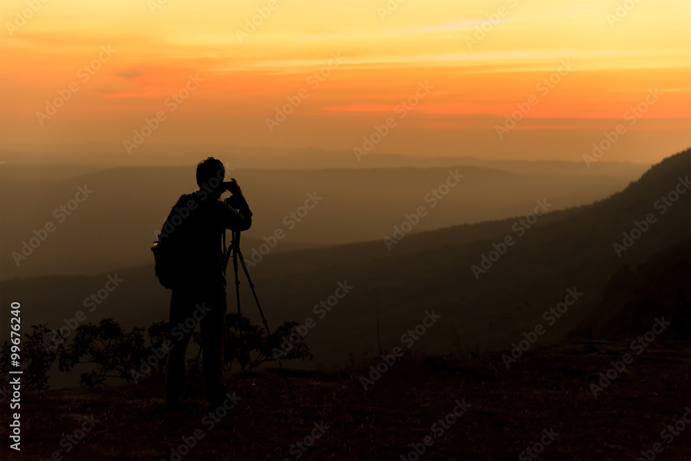 Silhouette of traveler when he is taking photograph on mountain