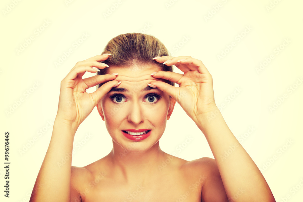 Young woman checking wrinkles on her forehead Young woman checking wrinkles on her forehead