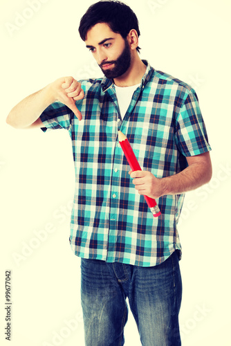 Young man holding big red pencil.