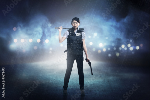Pretty woman in police vest holding baseball bat