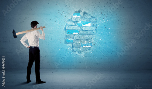 Business man hitting brick wall with huge hammer