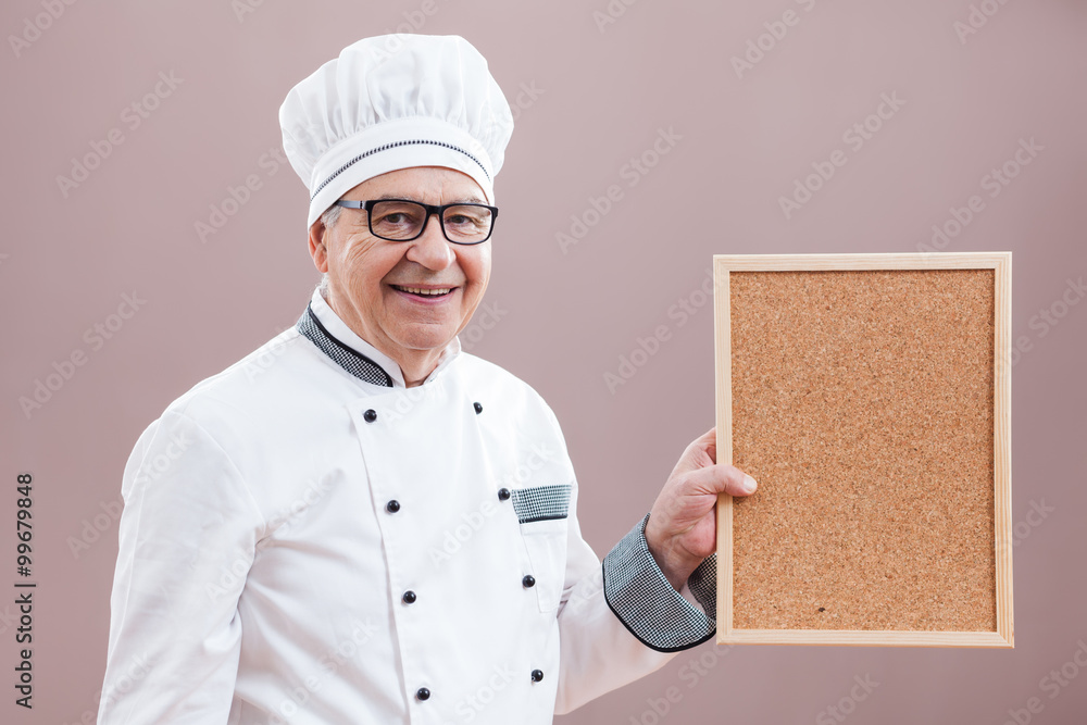 Portrait of restaurant's chef in working uniform showing what is on menu