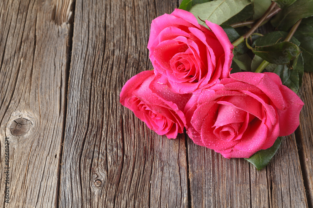 Three pink roses on wooden table