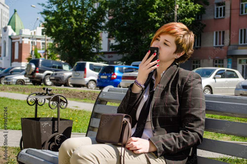 Young business woman with a phone working outdoor sitting on the