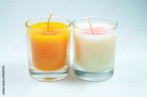 white and orange candles aroma in clear glass on white background