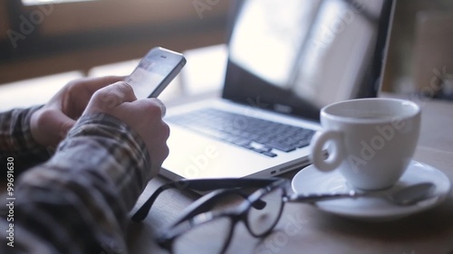 Side view shot of a man's hands using smart phone in interior, rear view of business man hands busy using cell phone at office desk