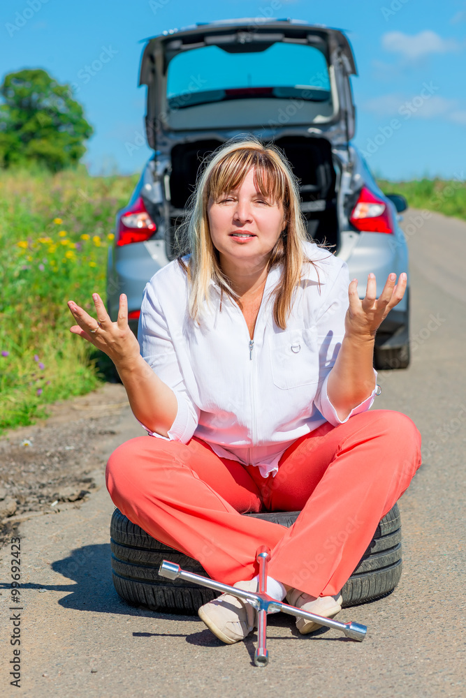 annoyed woman sitting on the bursting of the wheel and waiting f annoyed woman sitting on the bursting of the wheel and waiting f