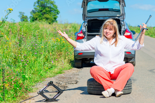angry female driver sitting at the wheel near the broken car