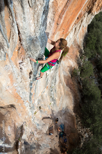 Extreme Sport Athlete hanging high on colorful rocky Wall