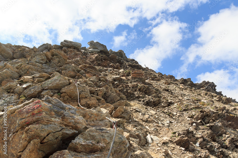 Steel cable from a via ferrata in a mountain rock face towards Säulkopf, Hohe Tauern Alps, Austria