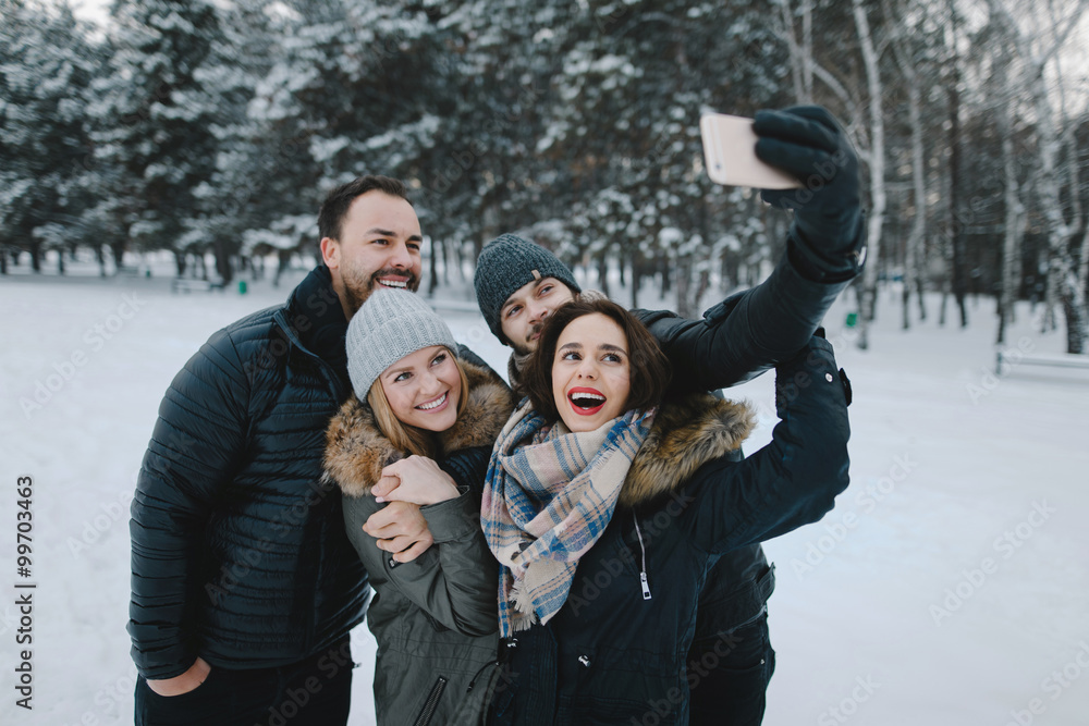 Fototapeta premium Cute young hipster couples posing in winter park on a bright day hugging each other and smiling 