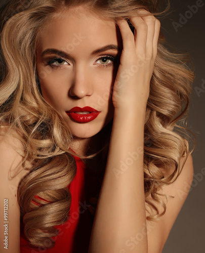 beautiful girl with blond curly hair and bright evening makeup  wears elegant dress