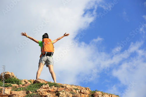 young woman backpacker climbing to mountain peak