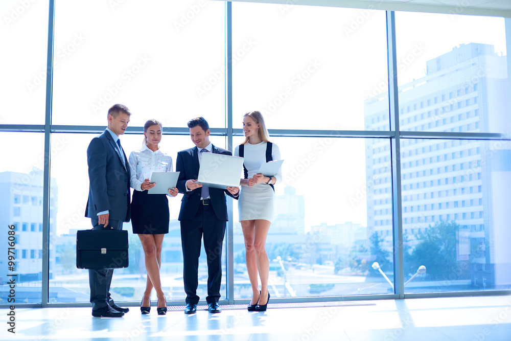 Smiling successful business team standing in office Smiling successful business team standing in office