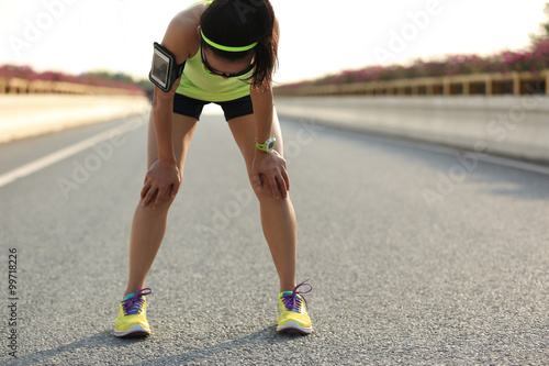 tired woman runner taking a rest after running hard on city road photo