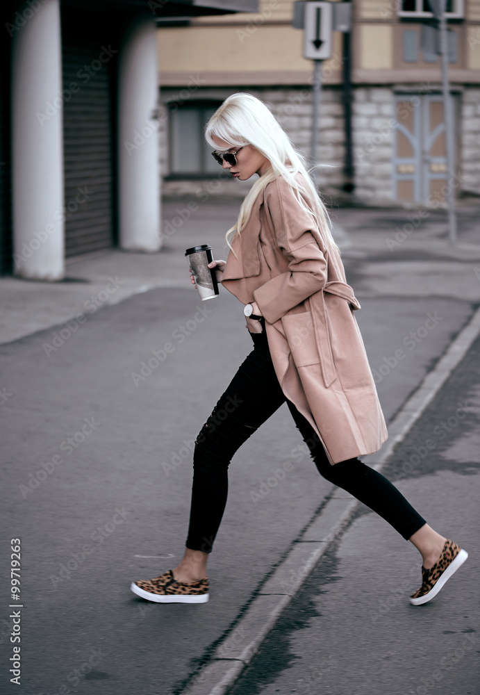 Beautiful blonde model walking outdoors with coffee Beautiful blonde model walking outdoors with coffee