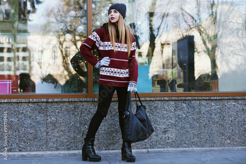 Street portrait of young beautiful woman with long blond hair wearing stylish winter clothes. Model looking aside. Female fashion concept