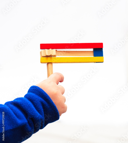 Принти на полотні A child's hand holding Colorful wooden noisemaker Purim holiday
