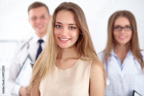 Happy smiling female patient with two cheerful doctors in the background. Medical and health care concept