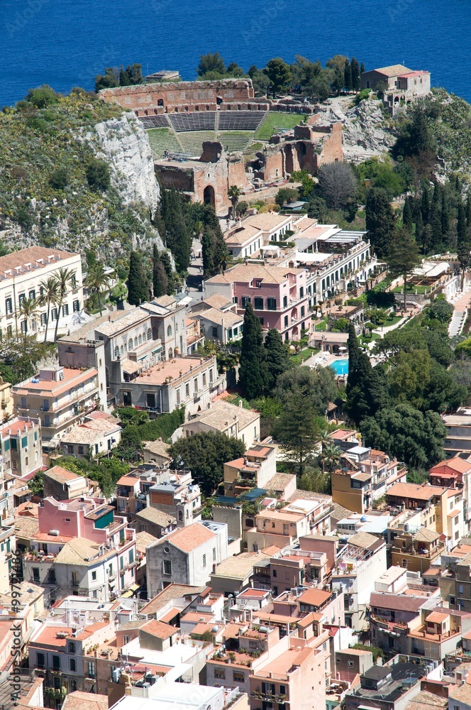 The ancient city of Taormina with the ruins of the Greek Roman theater from view , Sicily, Italy