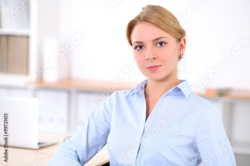 Young blonde business woman with laptop in the office. Business concept.
