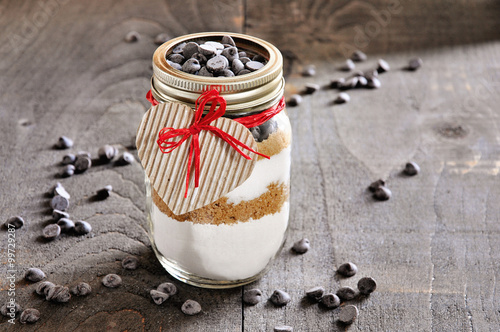 Chocolate chips cookie mix in glass jar. St. Valentine’s day gift concept, selective focus, toned image