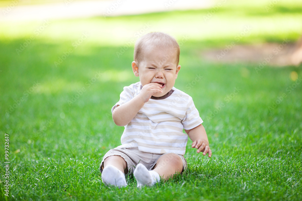 Little boy crying while sitting on grass in park Little boy crying while sitting on grass in park