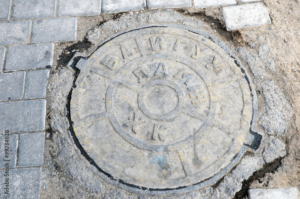 The hatch of urban sewerage with the inscription in the Mongolian language.   Ulaanbaatar, Mongolia