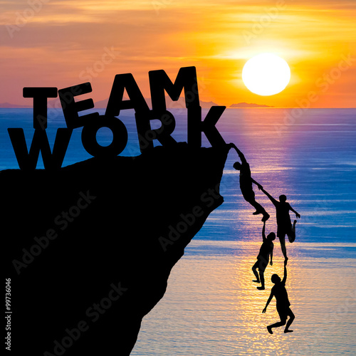 Silhouette teamwork of people climbs into cliff to reach the word TEAM WORK with sunrise (business concept)
