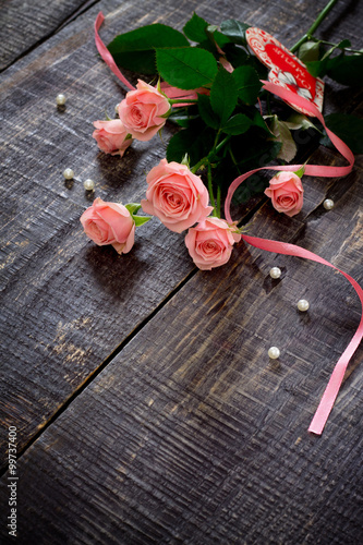 Beautiful pink roses on a dark wooden table, with space for text