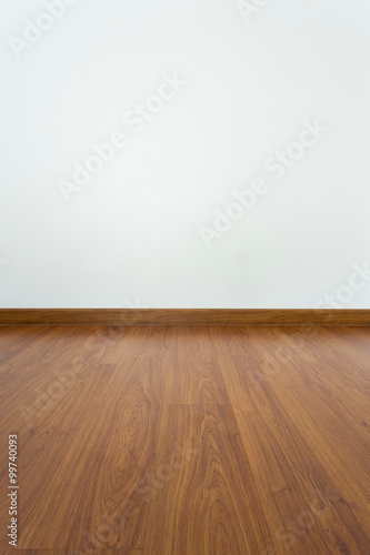 empty room with brown wood laminate floor and white mortar wall © sutichak
