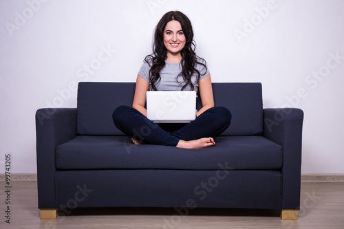 portrait of pretty woman sitting on sofa and using laptop at hom