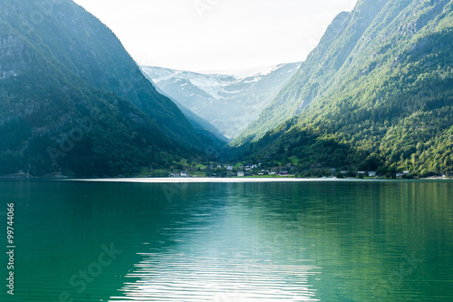 Norwegian fjord with small village surrounded by mountains cover
