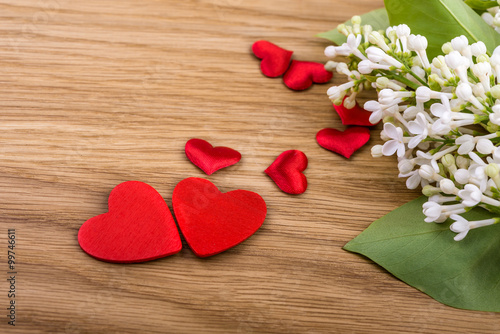 White lilac and hearts on wooden background