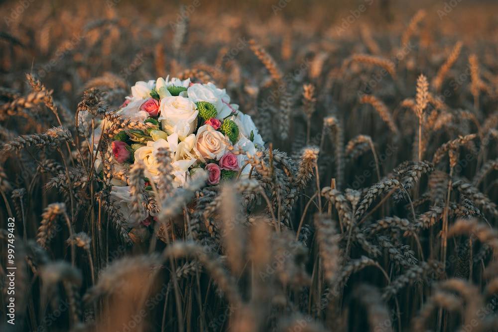 bridal bouquet lying on wheat
