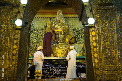 The monk is washing Mahamuni Buddha in ritual of the Buddha face wash in the morning at Mahamuni temple in Mandalay, Myanmar.