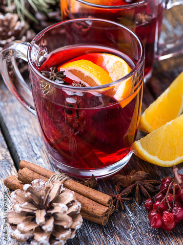 Hot drink, mulled wine red in a cup of glass on a wooden background