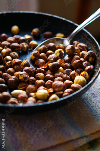 Roasted dried hazelnuts on iron pan with spoon